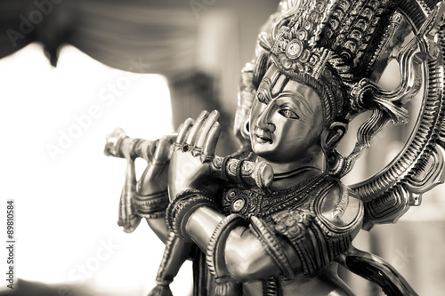 Black and white statue of the Hindu God Krishna playing a flute