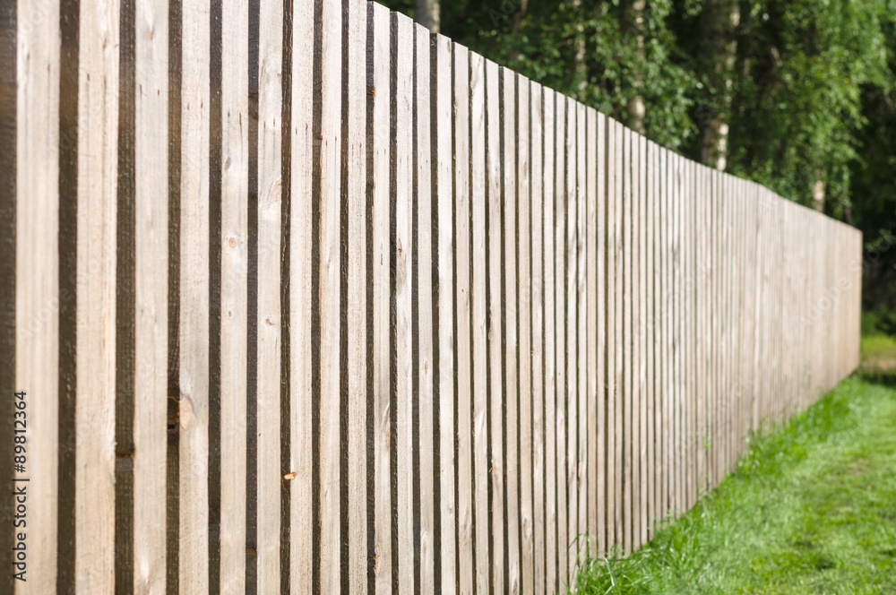 Typical wooden fence with green lawn and trees