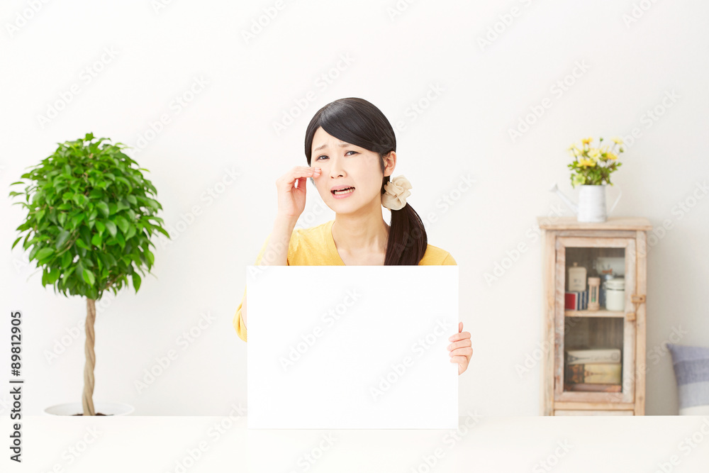 部屋でメッセージボードを持つ女性　泣く