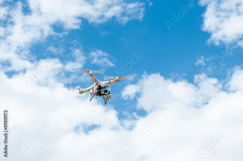 white drone hovering in a bright blue sky