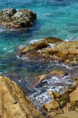 Rocky beach with clear blue water on a sunny day © inguaribile
