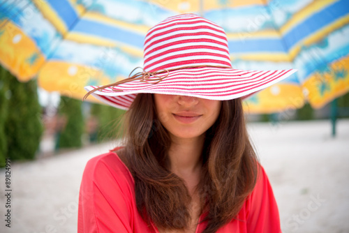 girl in the hat under umbrella on the sand