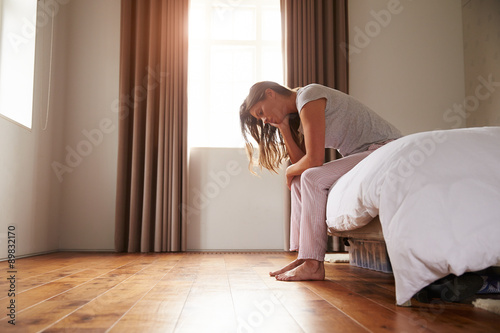 Woman Suffering From Depression Sitting On Bed In Pajamas © Monkey Business