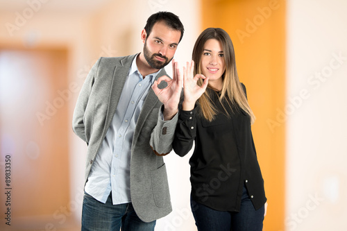 Couple making Ok sign over white background