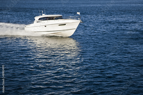 White motor boat sailing in calm water © Image Supply Co