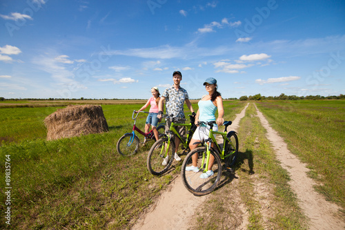 Happy family on bikes standing in a field