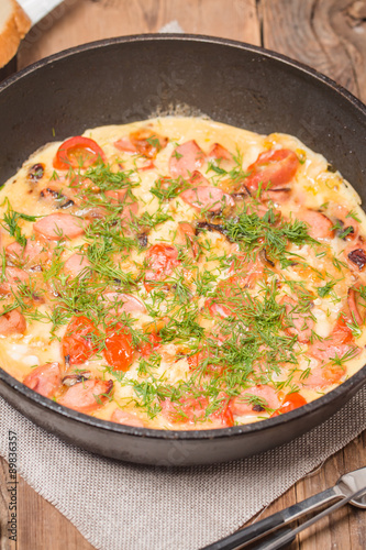 Omelette with sausage, onion, herbs and tomatoes