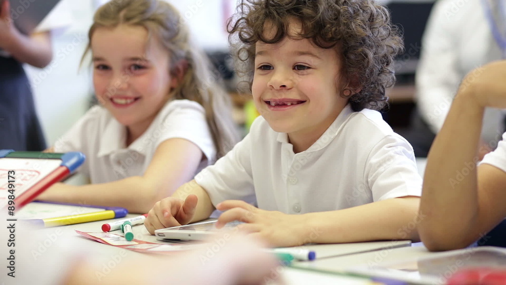 A small group of students look happy and smile while they are working on whiteboards and digital tablets at school. A small group of students look happy and smile while they are working on whiteboards and digital tablets at school.