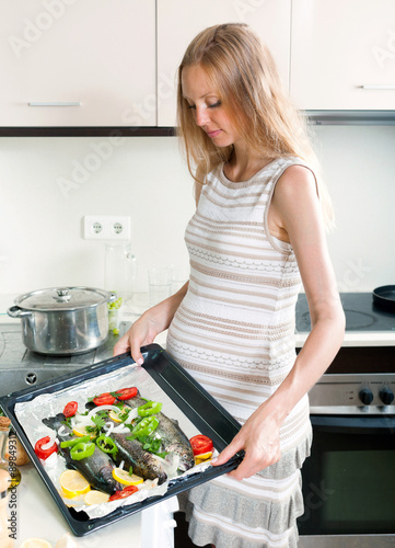 Woman cooking trout fish in pan