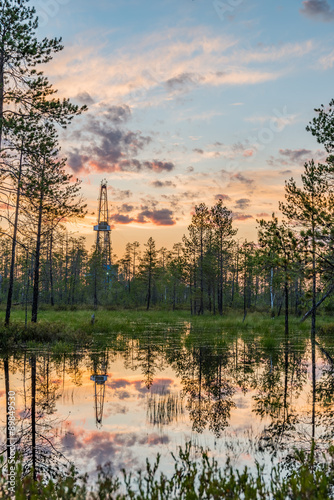 Fotografia Siberian swamps under sunset skies with land oil drilling rig reflecting in wate