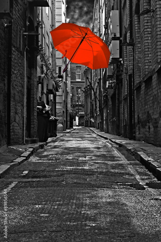 Fototapeta Naklejka Na Ścianę i Meble -  Red umbrella in a dark urban alleyway