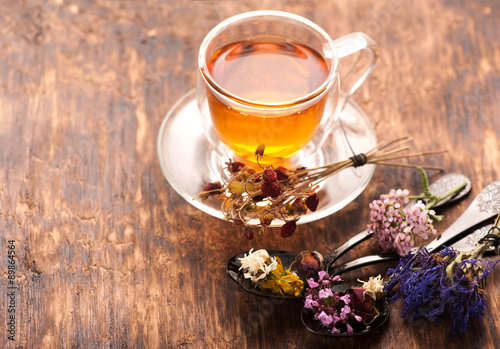 Obraz na plátně Cup of herbal tea with wild flowers and various herbs