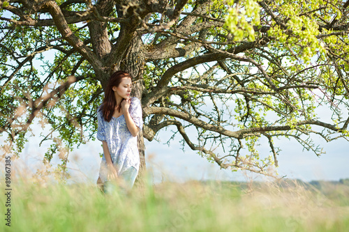 девушка в поле, стоящая возле дерева
