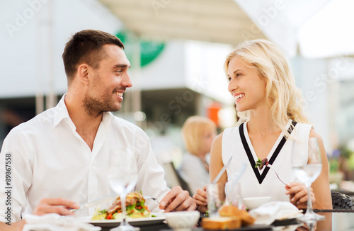 happy couple eating dinner at restaurant terrace