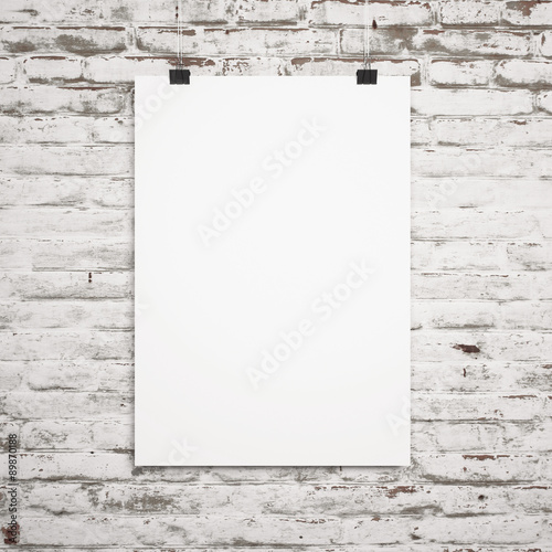blank poster hanging with clips on a background of white brick wall