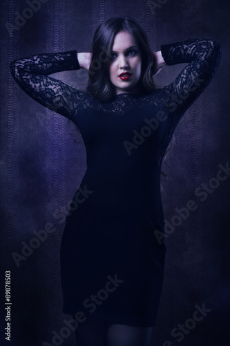 Pretty woman in a black dress in the dark room