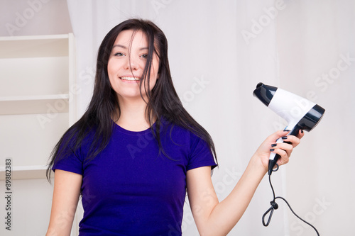 Foto Funny girl uses hair dryer at bathroom