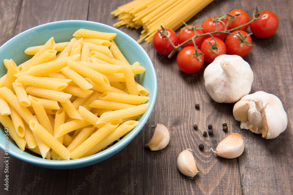 Mixed dried pasta selection on wooden background.