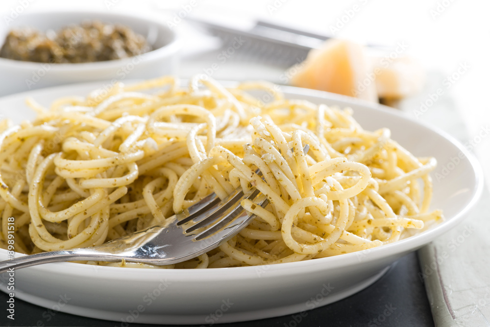 plate of spaghetti with pesto and cheese, selective focus