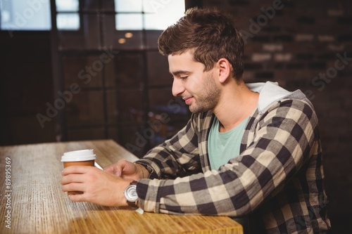Smiling hipster texting and holding take-away cup © WavebreakMediaMicro