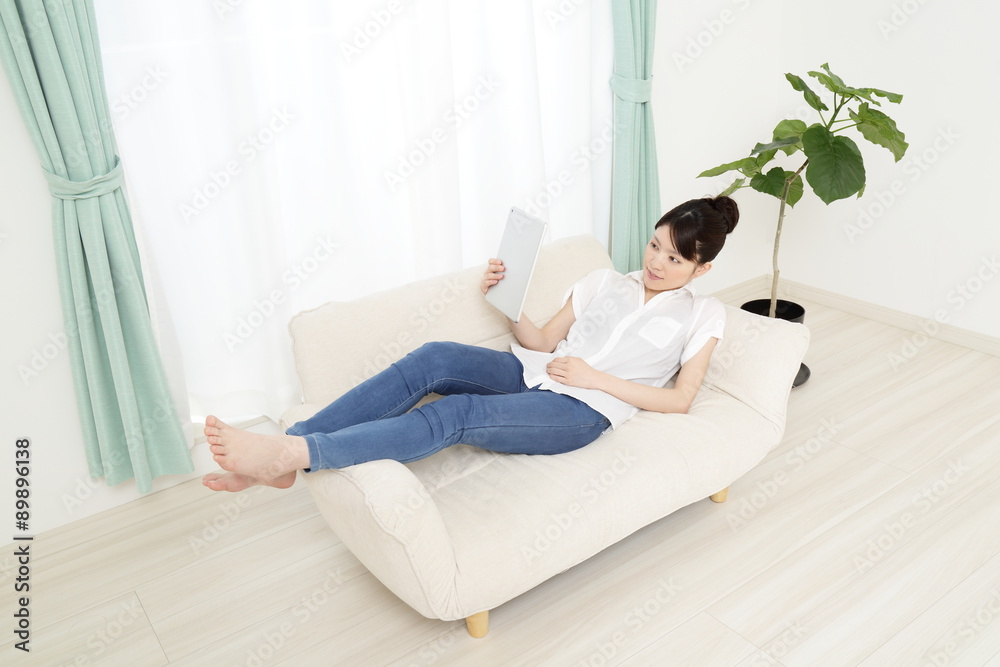 ソファーでタブレットを使っている女性 ソファーでタブレットを使っている女性