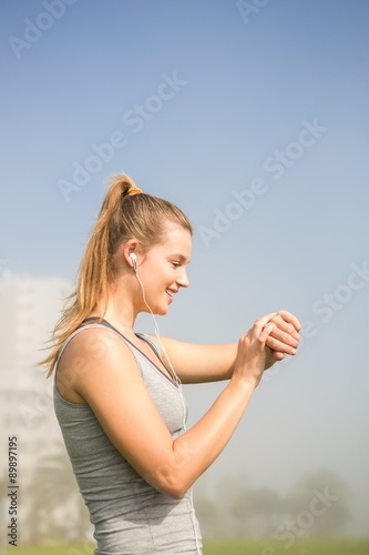 Smiling sporty blonde using smart watch