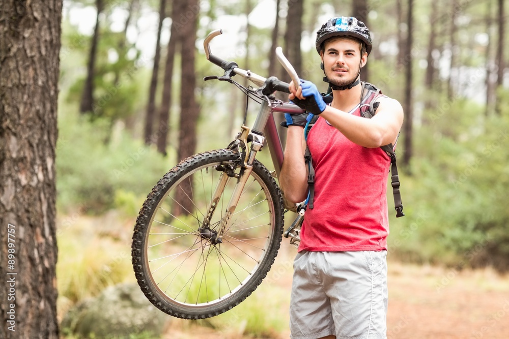 Fototapeta premium Happy handsome biker holding bike and looking at camera