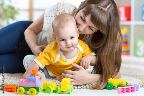 child boy and mother playing together with toys at home