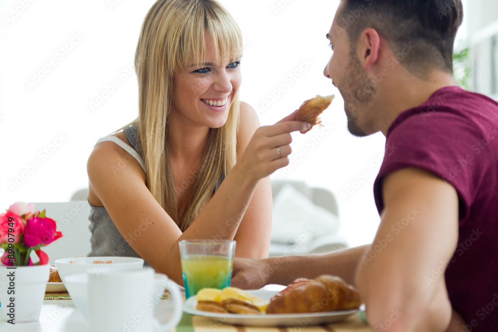 Happy young couple enjoying breakfast in the kitchen. Happy young couple enjoying breakfast in the kitchen.