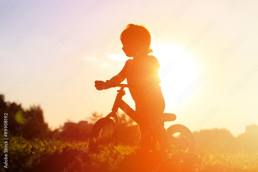 Fototapeta premium little girl riding bike at sunset