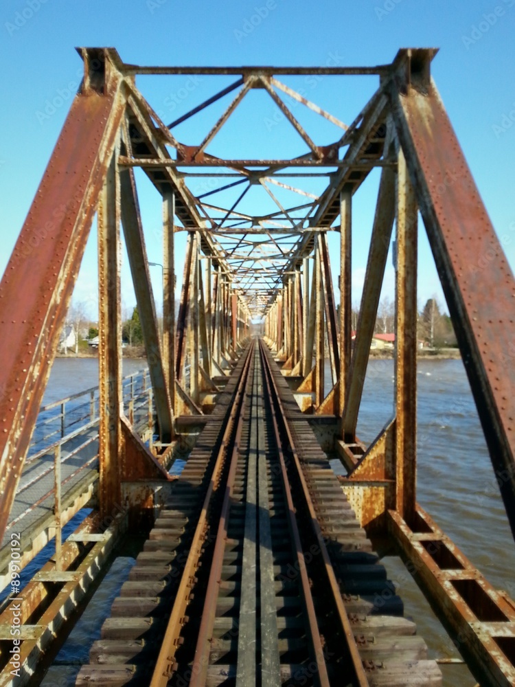 Railway bridge on sunny day. Heavy steel construction.
