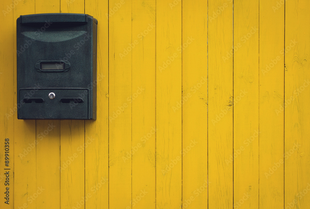 Old mailbox on a yellow wooden background