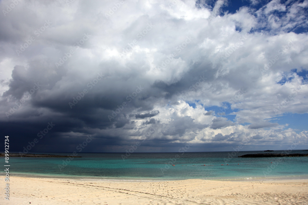 Sunny beach, dark clouds and turquoise water. Paradise Island, Bahamas