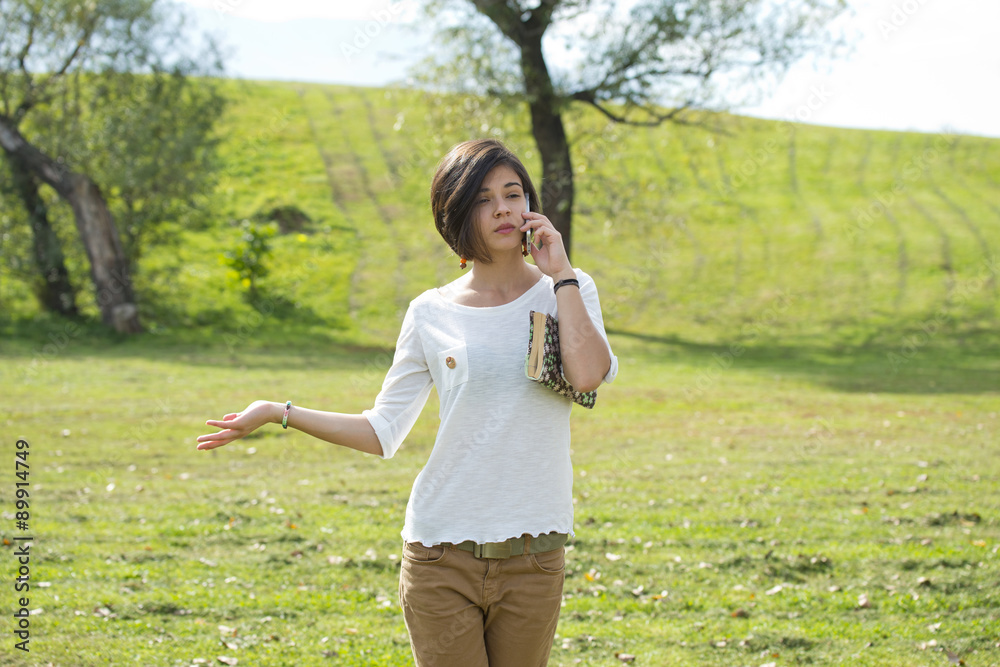 Beautiful young woman looks annoyed while talking on the phone Beautiful young woman looks annoyed while talking on the phone