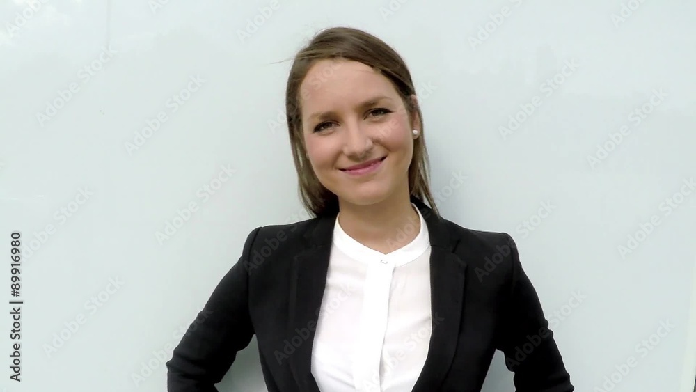 Business woman smiling tat camera and look around in the city by white glass wall. Business woman smiling tat camera and look around in the city by white glass wall.