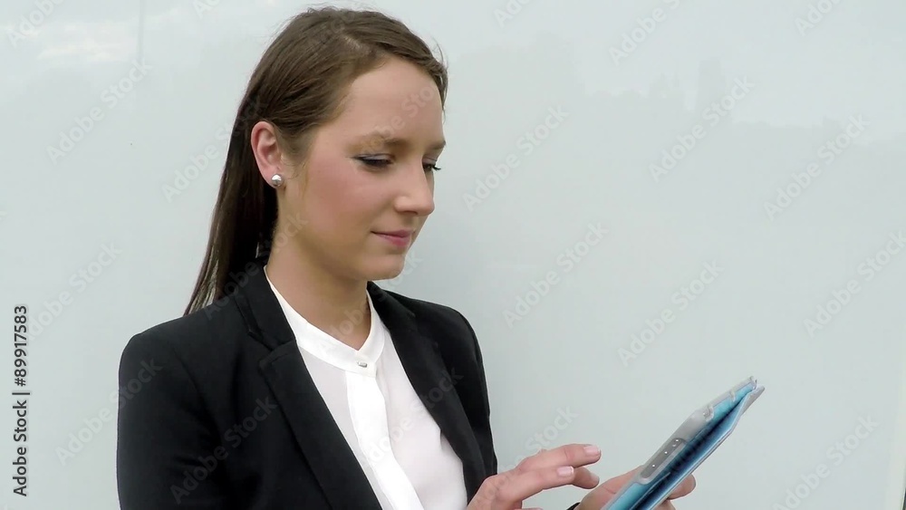 Business woman browsing internet on tablet against white wall in the city. Business woman browsing internet on tablet against white wall in the city.