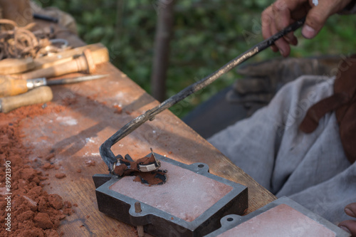 Handwerker entnimmt frisch gegossenen Bronzering photo