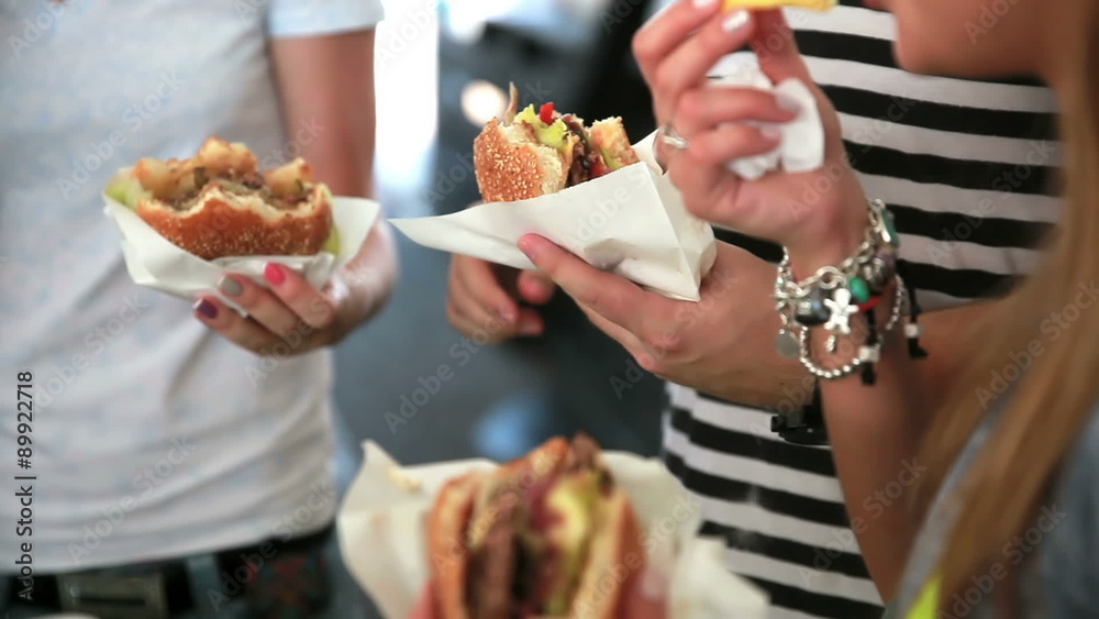 Young people eat burgers and fries on the street