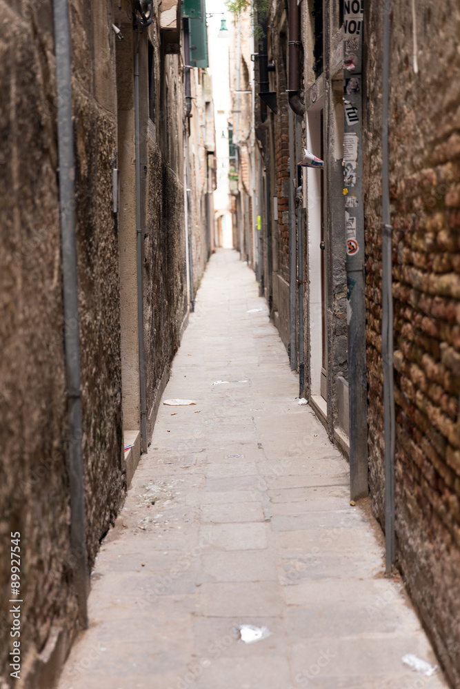 A narrow passage between the gloomy houses. Venice is one of the most popular tourist destinations in the world A narrow passage between the gloomy houses. Venice is one of the most popular tourist destinations in the world
