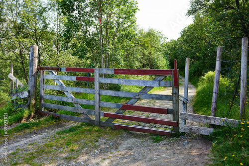 Closed old wooden gate protecting dirt road