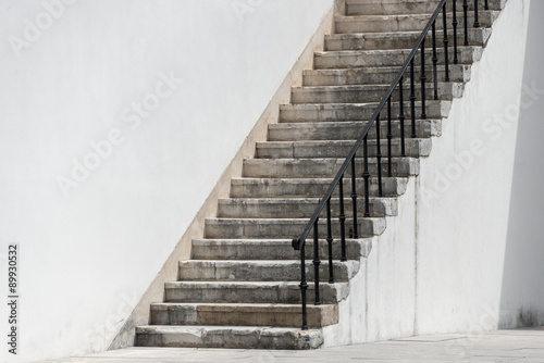 Tableau sur toile Stone stairs with a black iron banister descend to a stone flagged courtyard