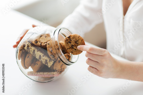 close up of hands with chocolate cookies in jar photo