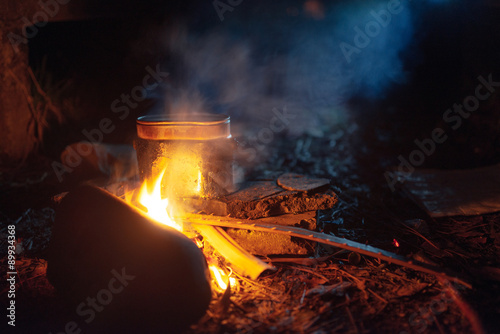 food is cooked in pot over a campfire at night