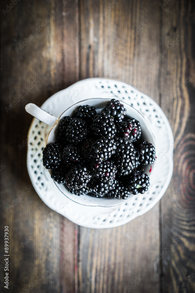 Blackberries in a mug on wooden background Blackberries in a mug on wooden background