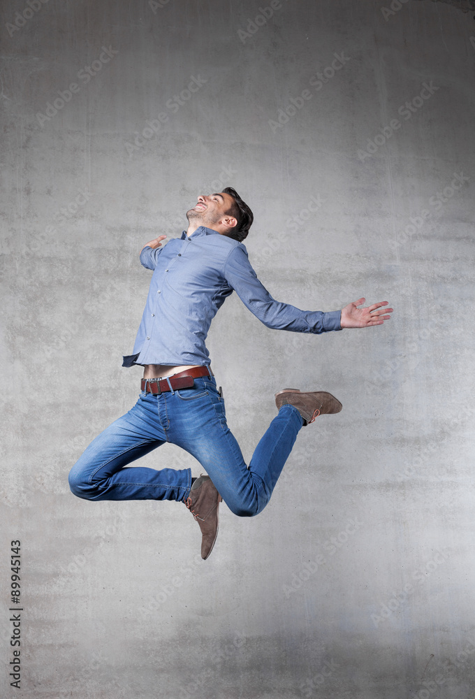 young man jumps in front of wall.