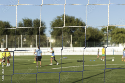 Rear view of soccer goal net  with children training at background  out of focus