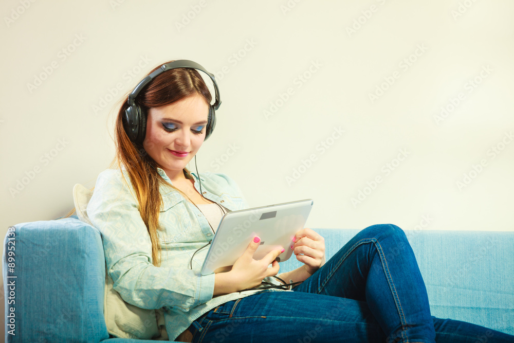 Woman with tablet headphones sitting on couch Woman with tablet headphones sitting on couch
