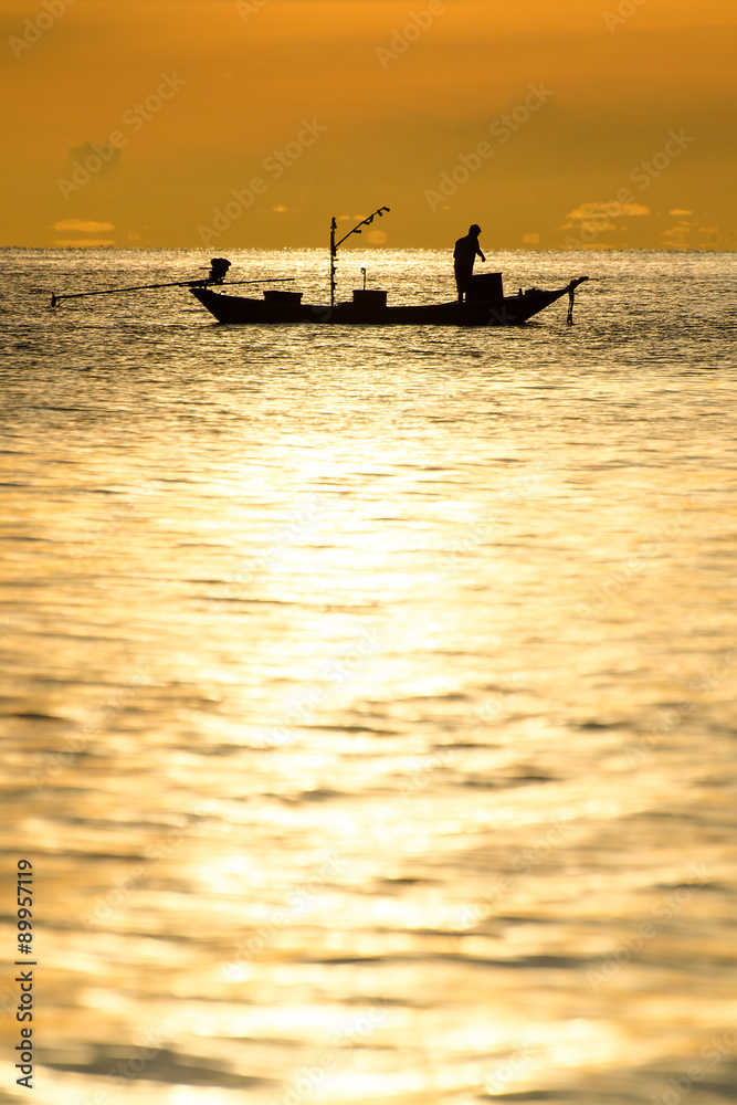 silhouette of fishermen in the boat on sea with yellow and orange sun in the background