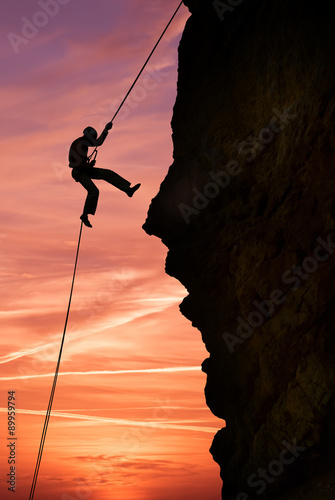 Silhouette of extreme rock climber against beautiful sunset