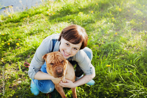 Obraz na płótnie laughing happy young woman in denim overalls hugging her red cute dog Shar Pei i
